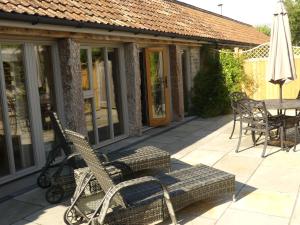 um pátio com uma mesa, cadeiras e um guarda-sol em Pear Tree Cottages em Wedmore