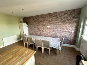 uma sala de jantar com mesa e cadeiras e uma parede de tijolos em Sandy Lodge em Hornsea