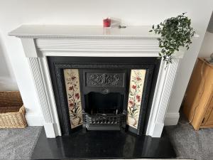 a fireplace with a white mantel and a plant at Sandy Lodge in Hornsea