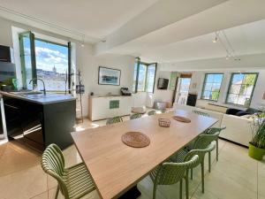 cocina y sala de estar con mesa de madera y sillas en GITE LA VUE LOIRE Maison en Saint-Denis-de lʼHôtel