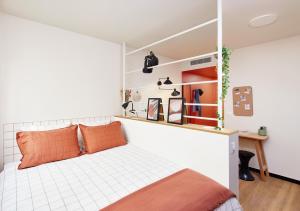 ein Schlafzimmer mit einem Bett mit orangefarbenen Kissen in der Unterkunft Hife Paris Issy in Issy-les-Moulineaux