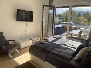 1 dormitorio con 1 cama, TV y ventana en FerienwohnenAmSee Penthouse mit Whirlpool, en Überlingen