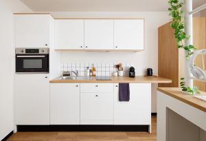 a white kitchen with white cabinets and a sink at Hife Paris Issy in Issy-les-Moulineaux