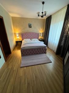 Schlafzimmer mit einem großen Bett mit einem rosa Kopfteil in der Unterkunft Pensiunea Sun Victor in Baile Felix