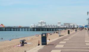 a group of people on a beach near a pier at Cosy home with FREE PARKING and fast internet in Portsmouth