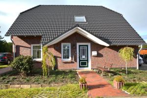 a small brick house with a black roof at Pension Lütje Huske Zimmer 1 in Südbrookmerland