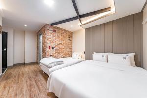 duas camas num quarto com uma parede de tijolos em Number 25 Gyeongju City Hall em Gyeongju