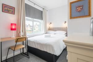 ein Schlafzimmer mit einem Bett, einem Fenster und einem Stuhl in der Unterkunft Central 4 Bed Home With Parking in Cambridge