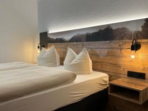 a hotel room with a bed with white pillows at Hotel Alpenhof Bayrischzell in Bayrischzell +23 photos