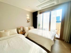two beds in a room with a window at Morning Madrid in Jeju
