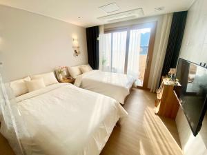 a hotel room with two beds and a large window at Morning Madrid in Jeju