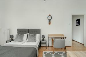 a bedroom with a bed and a clock on the wall at Cosy Studio in the Centre of Poznań with Balcony by Renters in Poznań