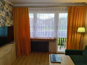 a living room with a window and a laptop on a table at Miętówka in Żywiec