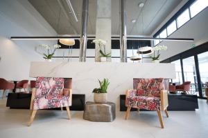 a lobby with two chairs and a table with a fireplace at Arrow Hôtel EuroAirport Bâle Mulhouse in Hégenheim +39 photos