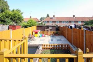 a backyard with a yellow fence and a garden at 3 Beds Sleeps 8 House Near California Cliffs Park in Norwich