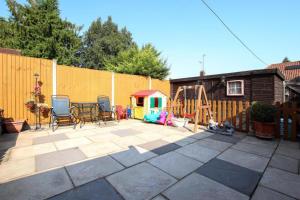 een patio met stoelen en een speeltuin in de achtertuin bij 3 Beds Sleeps 8 House Near California Cliffs Park in Norwich