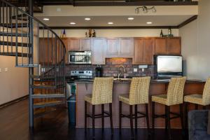 a kitchen with a bar with chairs and a staircase at Marlin at the Lake - Downtown Sandusky in Sandusky