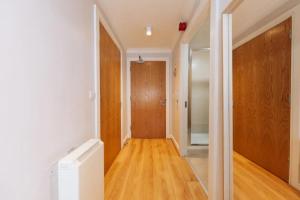 an empty hallway with a door and wooden floors at Chic & Radiant 1BD Flat near Dublin City Centre! in Dublin