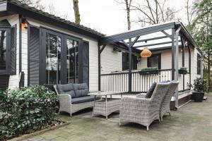 a porch with wicker chairs and a pergola at Chalet op familiepark Veluws Hof op de Veluwe in Hoenderloo