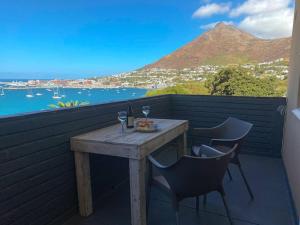 a wooden table with two wine glasses on a balcony at Lock up & go apt w/ great views in Simons Town in Cape Town