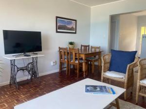 a living room with a television and a table with chairs at Lock up & go apt w/ great views in Simons Town in Cape Town
