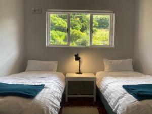 two twin beds in a room with a window at Lock up & go apt w/ great views in Simons Town in Cape Town