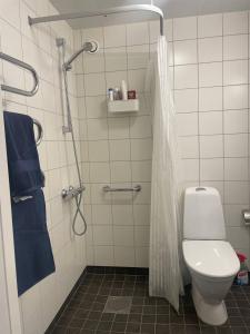 a bathroom with a toilet and a shower with blue towels at The favorite room in a shared apartment in Nacka