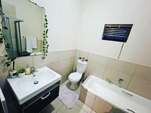 a bathroom with a sink and a toilet and a mirror at Luxurious Exclusive Home In A Golf Estate in Roodepoort