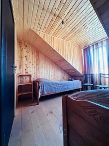 een kamer met een bed in een houten huis bij Guest House MARGALITI-საოჯახო სასტუმრო მარგალიტი in Omalo