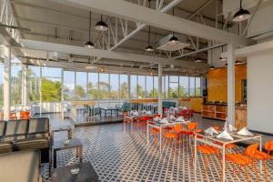 een restaurant met oranje stoelen en tafels en ramen bij Bedzzz Xclusiv Morjim, Goa By Leisure Hotels in Morjim