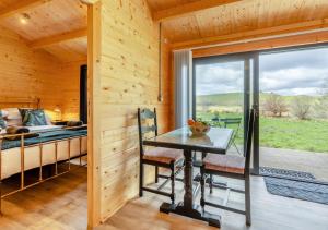 a wooden cabin with a table and chairs and a bed at Foxglove Cabin in Devils Bridge