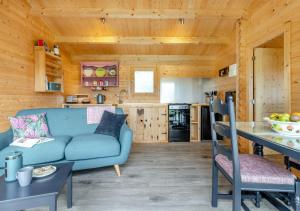a living room with a blue couch and a kitchen at Foxglove Cabin in Devils Bridge