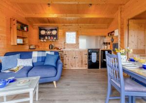 a living room with a blue couch and a kitchen at Bluebell Cabin in Devils Bridge