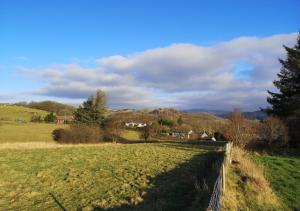 a field with a fence and trees in the distance at Rose Cabin in Devils Bridge