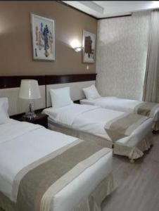 a hotel room with three beds in a room at Arfalon Hotel and Tourism in Makkah