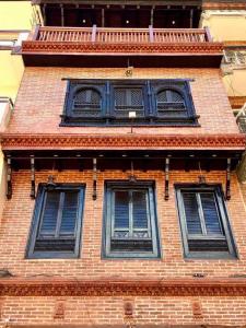 drie ramen op een bakstenen gebouw met blauwe luiken bij Shahi Studio Apartment in Pātan