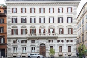 un grand bâtiment blanc avec une voiture garée devant. dans l'établissement The Best in Rome Orologio, à Rome