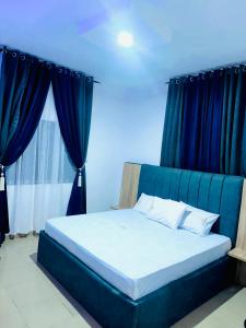 een bed in een kamer met blauwe gordijnen bij D Governor's Place & Apartments in Port Harcourt