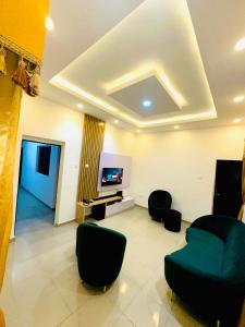 een woonkamer met stoelen en een flatscreen-tv bij D Governor's Place & Apartments in Port Harcourt