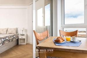 una habitación con una mesa con un plato de cruasanes y un dormitorio en MyHouseSpain - Primera línea de playa con parking, en Gijón