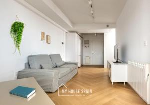 sala de estar con sofá y TV en MyHouseSpain - Primera línea de playa con parking, en Gijón