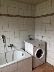 a bathroom with a washing machine next to a tub at Ferienwohnung Maria in Wimbach