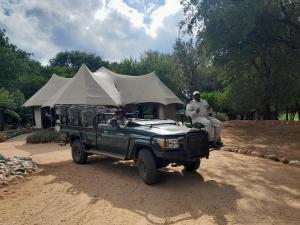 a man riding a jeep in front of a tent at Karongwe Portfolio - Chisomo Safari Camp in Karongwe Game Reserve