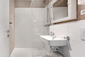 a white bathroom with a sink and a shower at Ferienwohnung Meerblick in Strande +11 photos