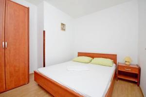 een slaapkamer met een wit bed en een houten kast bij Apartments Ivan in Novalja