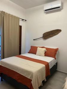 a bedroom with a bed with orange and white sheets at Paraíso à Beira-Mar, Touros RN - Acomoda 6 pessoas in Touros