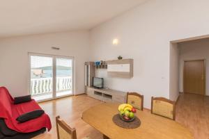 a living room with a table and a red chair at Apartments Rosanda in Pirovac