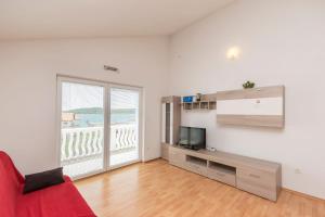 a living room with a red couch and a television at Apartments Rosanda in Pirovac