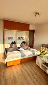 Schlafzimmer mit einem großen Bett mit einem Kopfteil aus Holz in der Unterkunft LUV & LEE Waterkant Ferienwohnung SPO in Sankt Peter-Ording