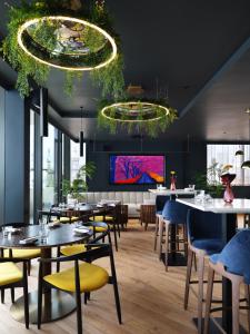 un restaurante con mesas y sillas y una pantalla grande en Malmaison Manchester Deansgate en Mánchester